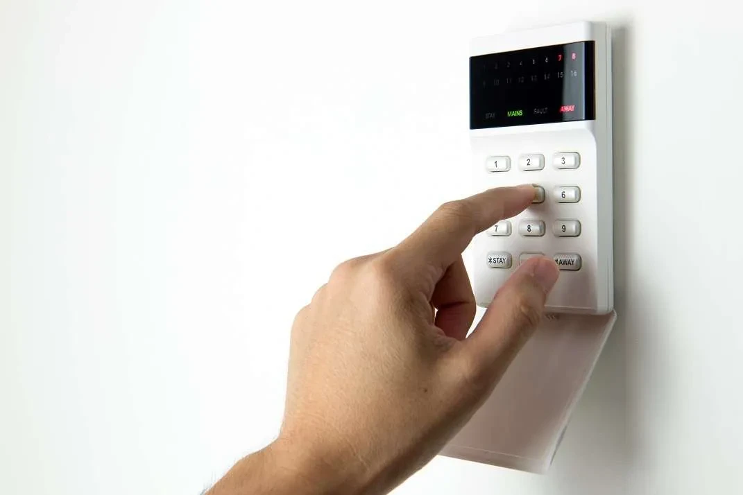 Hand entering code on a security alarm keypad